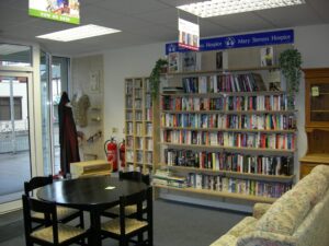 Bookcase filled with books and circle table and four chairs in charity shop