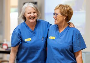 Two Hospice nurses smiling with arms around each other